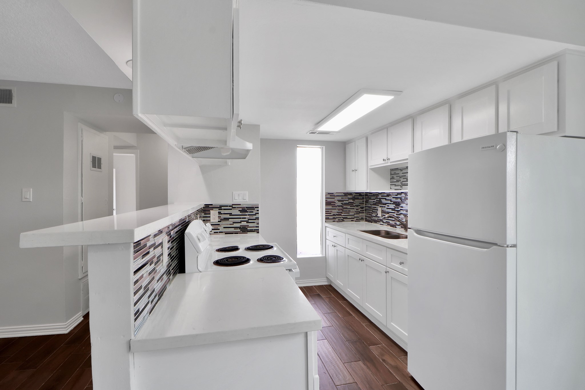 7047 Bissonnet Street, Unit 117 Houston, TX 77074 - Photo 6 of 17 a kitchen with kitchen island white cabinets and white appliances