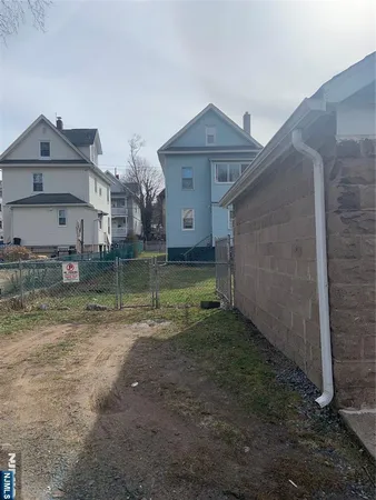 a view of a brick house next to a yard with wooden fence