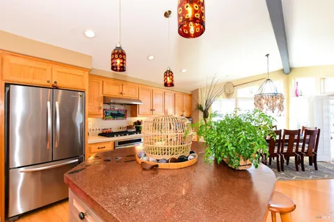 a kitchen with stainless steel appliances kitchen island granite countertop a sink a refrigerator and a counter space