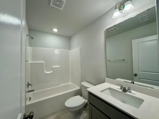 a bathroom with a sink a toilet a mirror and shower