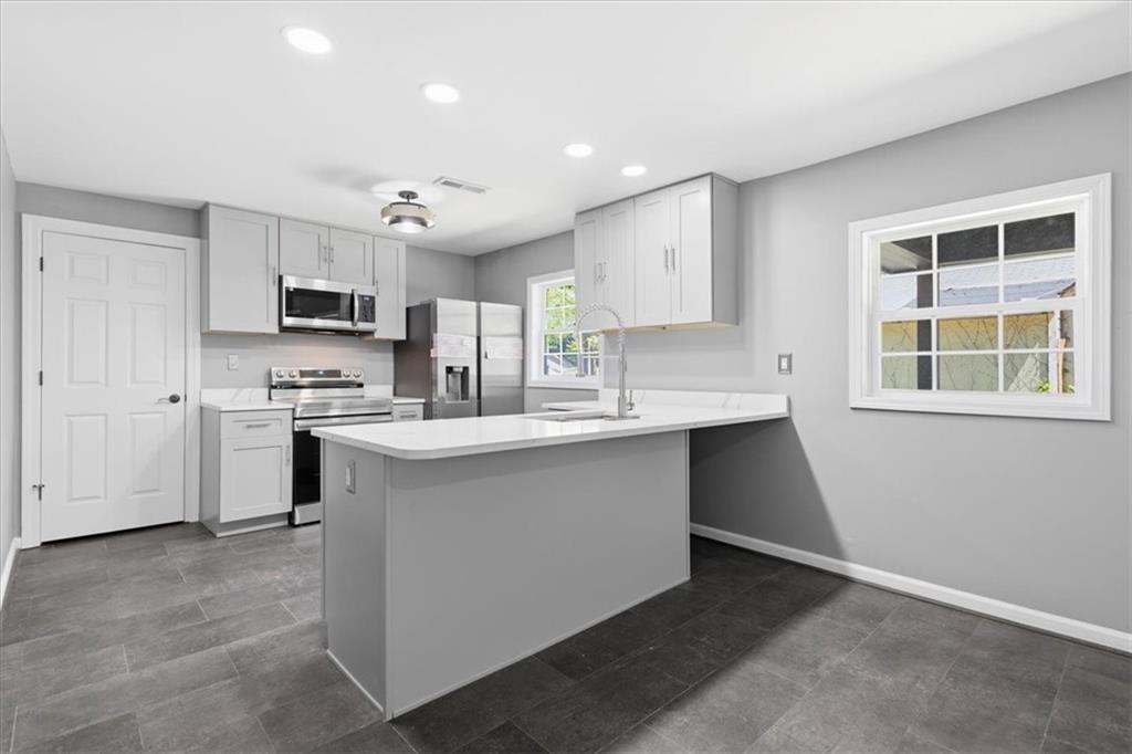 409 Calhoun Avenue Northeast Rome, GA 30161 - Photo 13 of 25 a kitchen with kitchen island a sink stainless steel appliances and cabinets