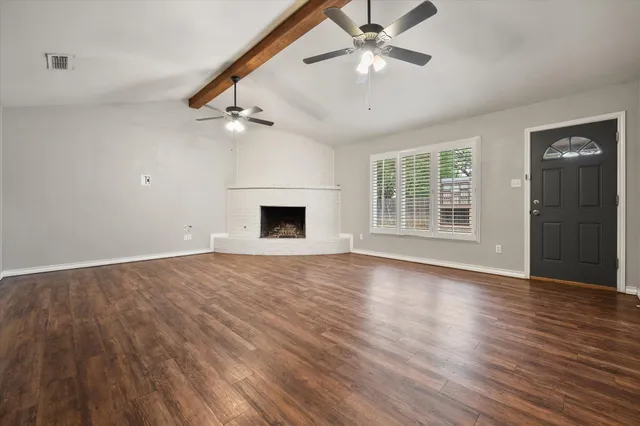 an empty room with wooden floor ceiling fan and windows