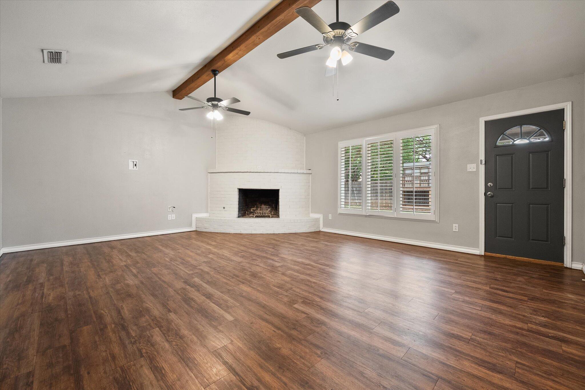 5309 77th Street Lubbock, TX 79424 - Photo 12 of 37 an empty room with wooden floor ceiling fan and windows