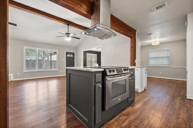 a view of a kitchen with wooden floors and stainless steel appliances