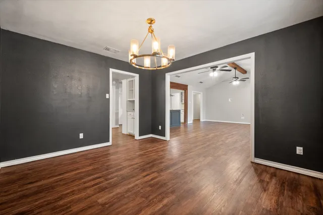 a view of a livingroom with a chandelier fan and wooden floor