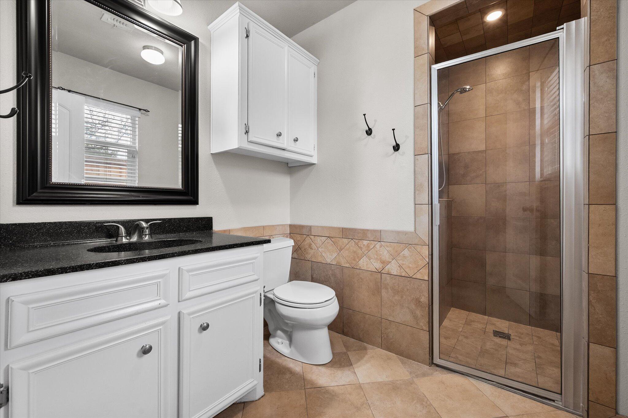 5309 77th Street Lubbock, TX 79424 - Photo 27 of 37 a bathroom with a granite countertop sink toilet and shower