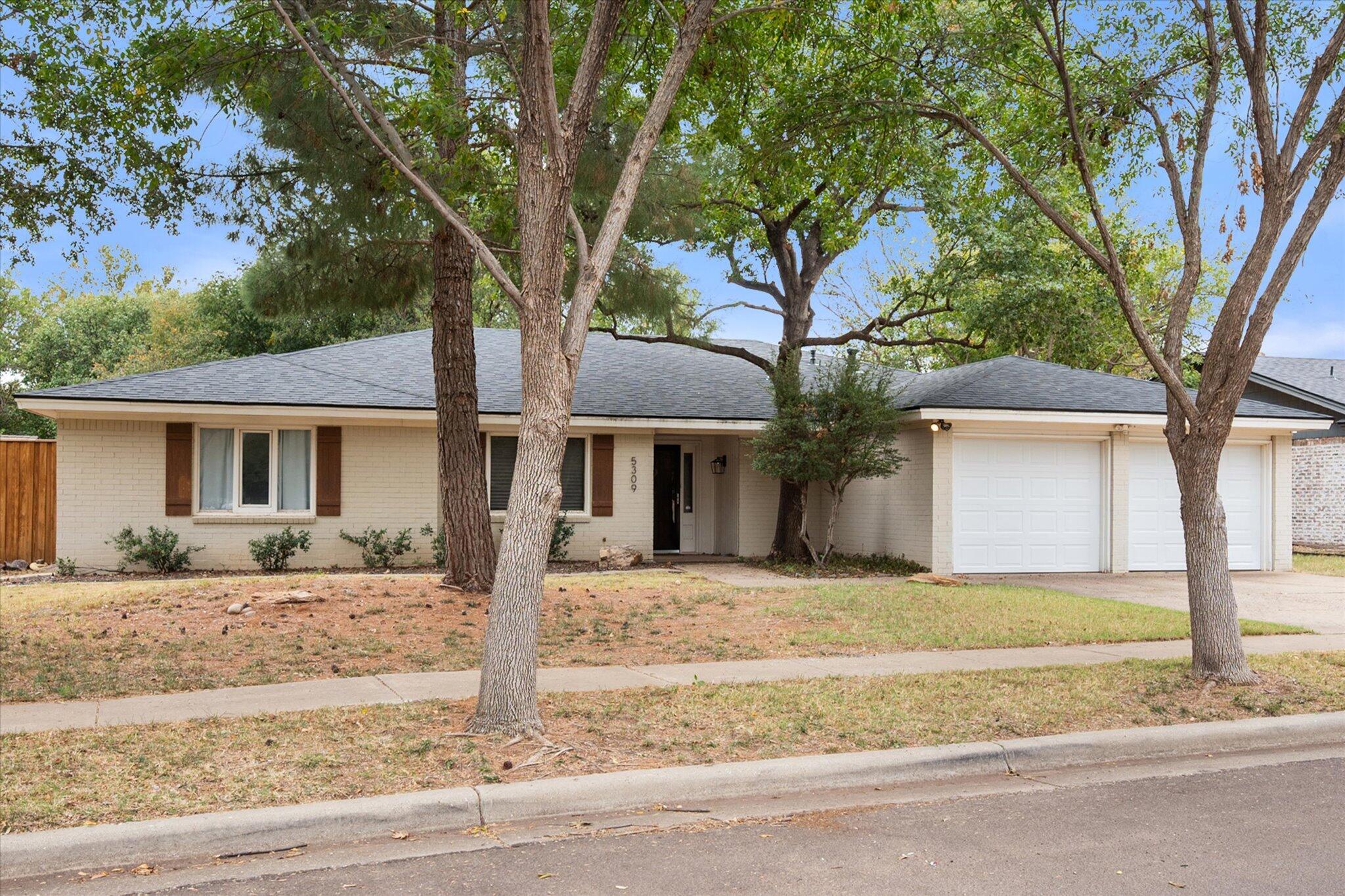 5309 77th Street Lubbock, TX 79424 - Photo 5 of 37 a front view of a house with garden and trees