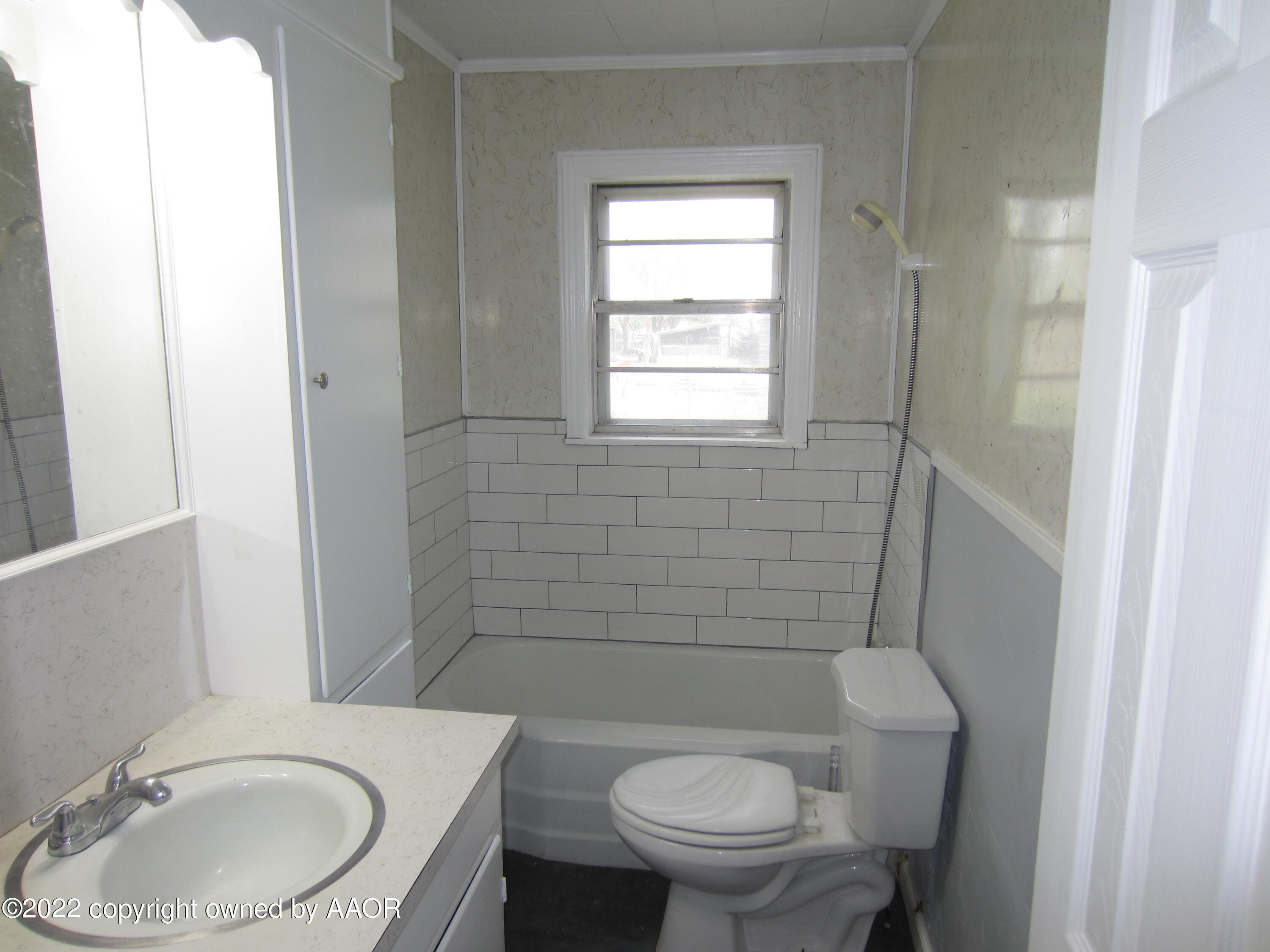 2002 North Mirror Street Amarillo, TX 79107 - Photo 9 of 13 a bathroom with a granite countertop toilet a sink and a mirror