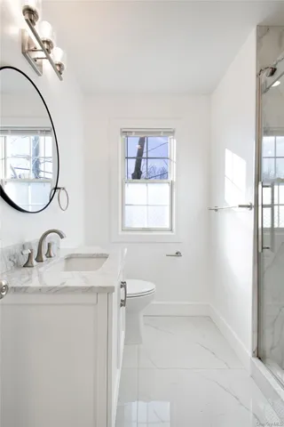 a bathroom with a granite countertop sink a mirror and a shower