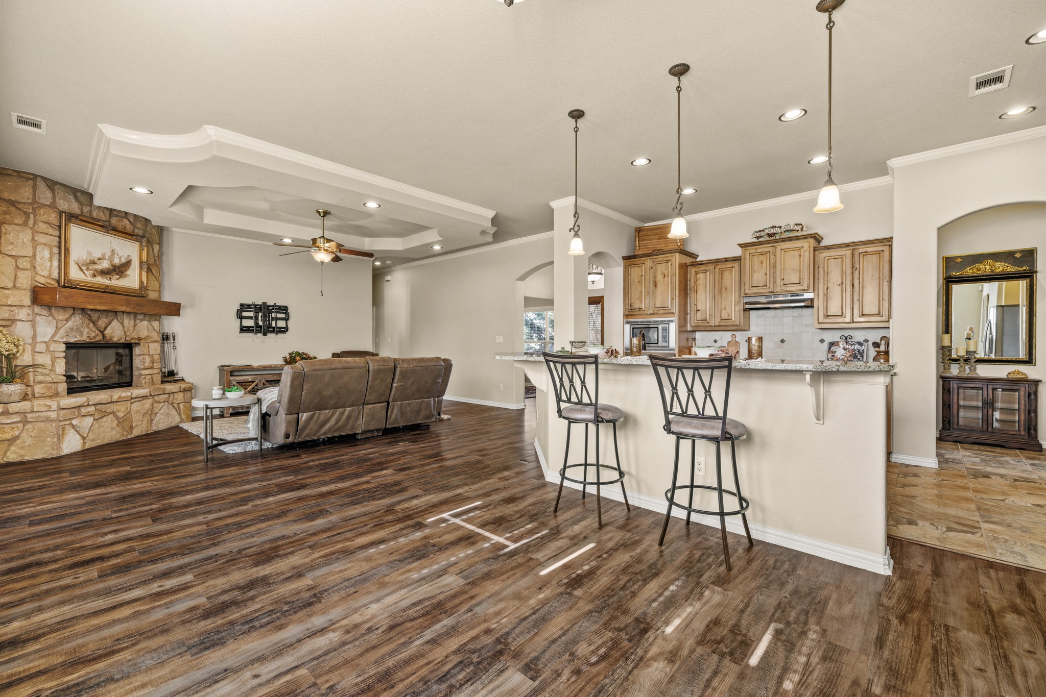 204 Skyline Road Georgetown, TX 78628 - Photo 39 of 40 Kitchen featuring arched walkways, a kitchen bar, a fireplace, open floor plan, and decorative light fixtures