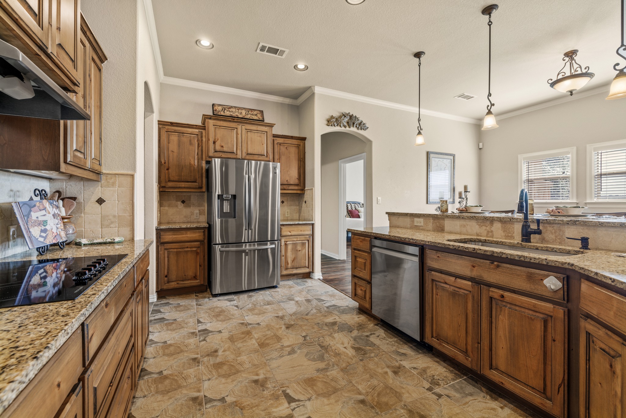 204 Skyline Road Georgetown, TX 78628 - Photo 16 of 40 Kitchen featuring stainless steel appliances, light stone countertops, ornamental molding, arched walkways, and decorative light fixtures