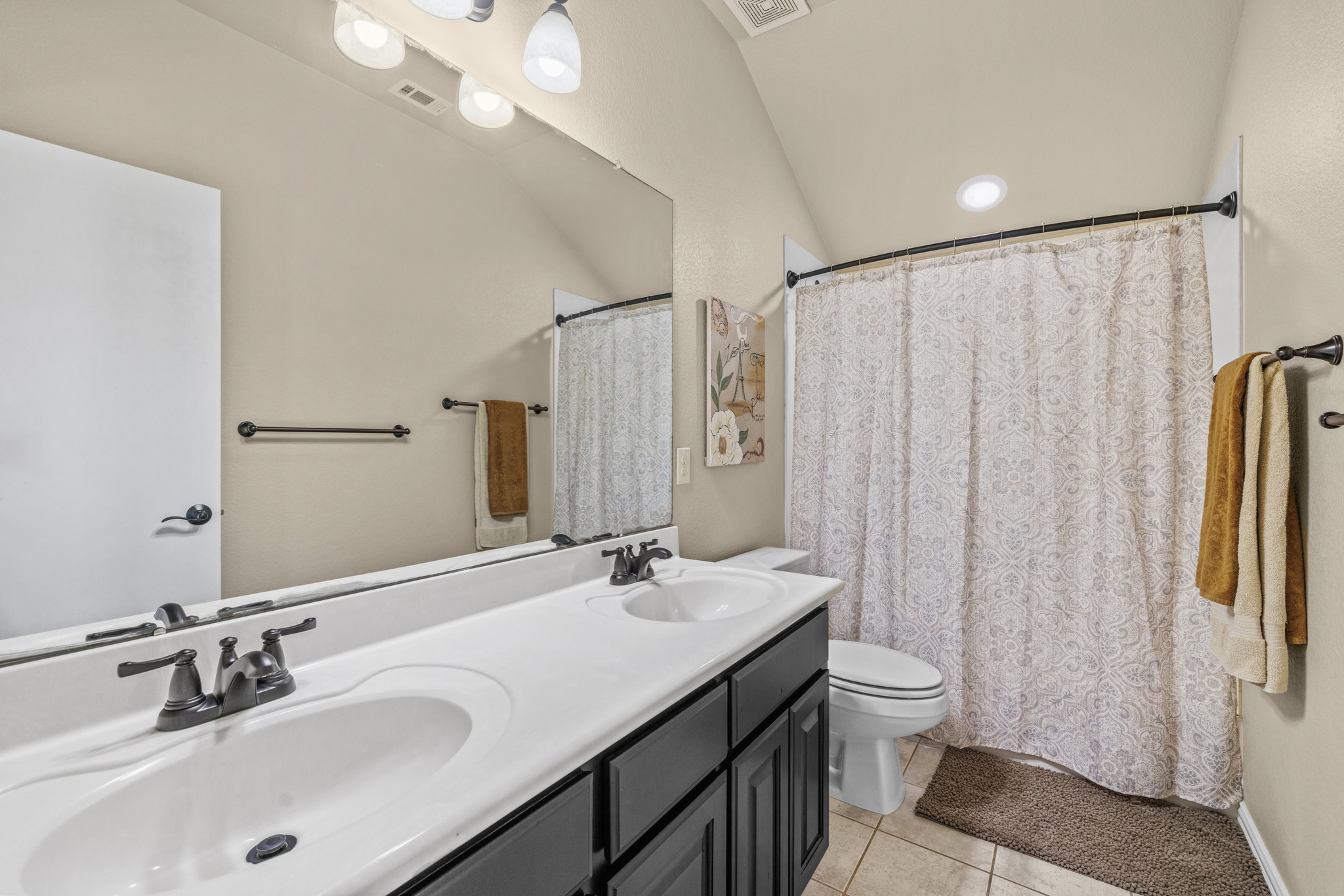 204 Skyline Road Georgetown, TX 78628 - Photo 29 of 40 Bathroom featuring double vanity, a shower with curtain, light tile patterned floors, and vaulted ceiling