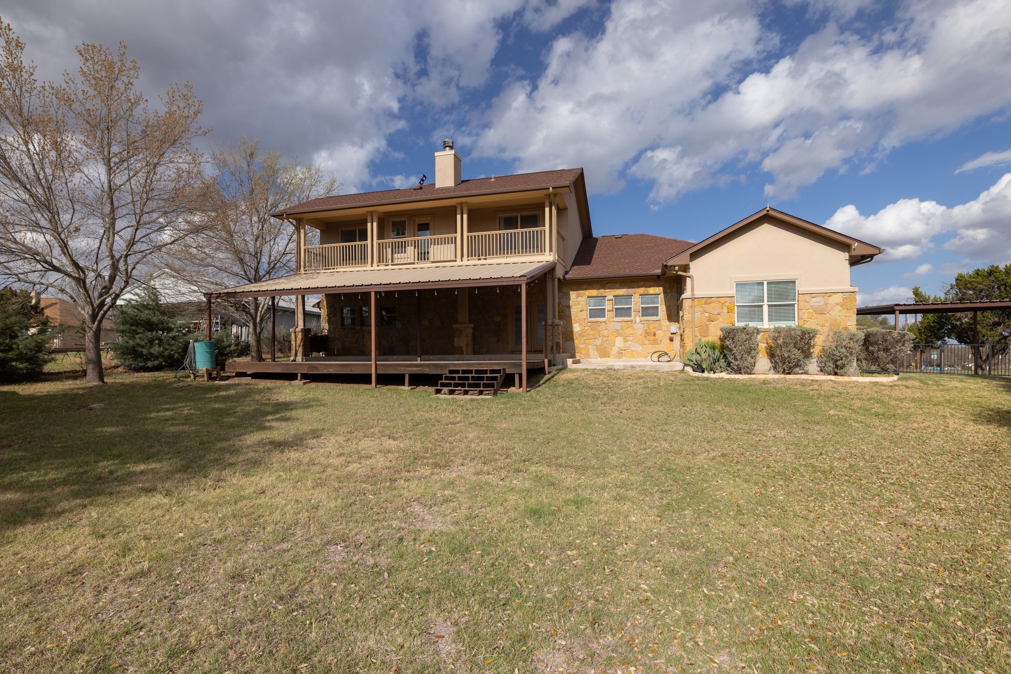 204 Skyline Road Georgetown, TX 78628 - Photo 36 of 40 Back of property featuring a lawn, covered porch, a chimney, stone siding, and stucco siding
