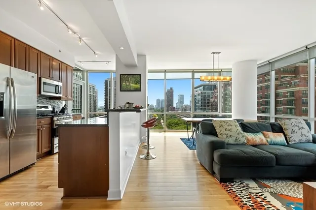 a living room with stainless steel appliances kitchen island granite countertop a couch a dining table and chairs