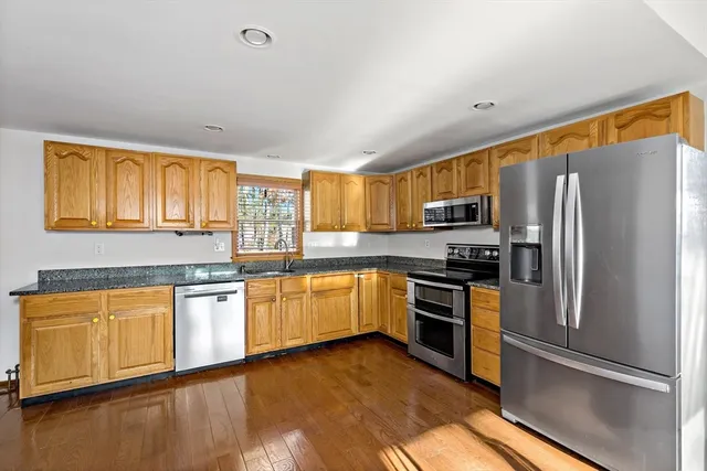 a kitchen with granite countertop stainless steel appliances a refrigerator cabinets and wooden floor