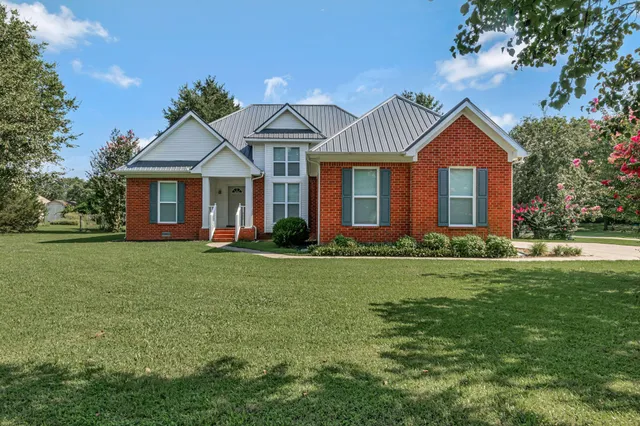 a front view of a house with a garden and yard