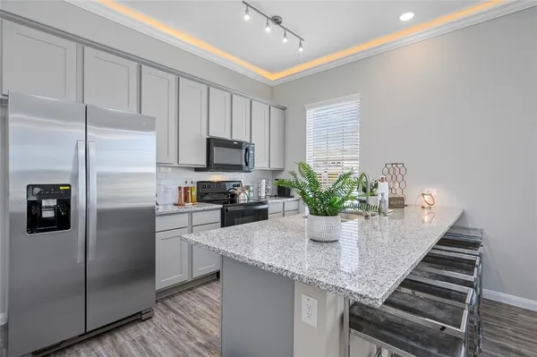 a kitchen with stainless steel appliances granite countertop a refrigerator a sink and white cabinets
