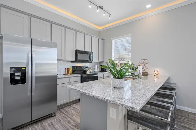 a kitchen with stainless steel appliances granite countertop a refrigerator a sink and white cabinets
