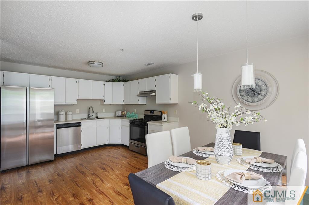 53 Prestwick Way Edison, NJ 08820 - Photo 11 of 28 a kitchen with granite countertop stainless steel appliances a sink dishwasher a microwave oven and a dining table with wooden floor