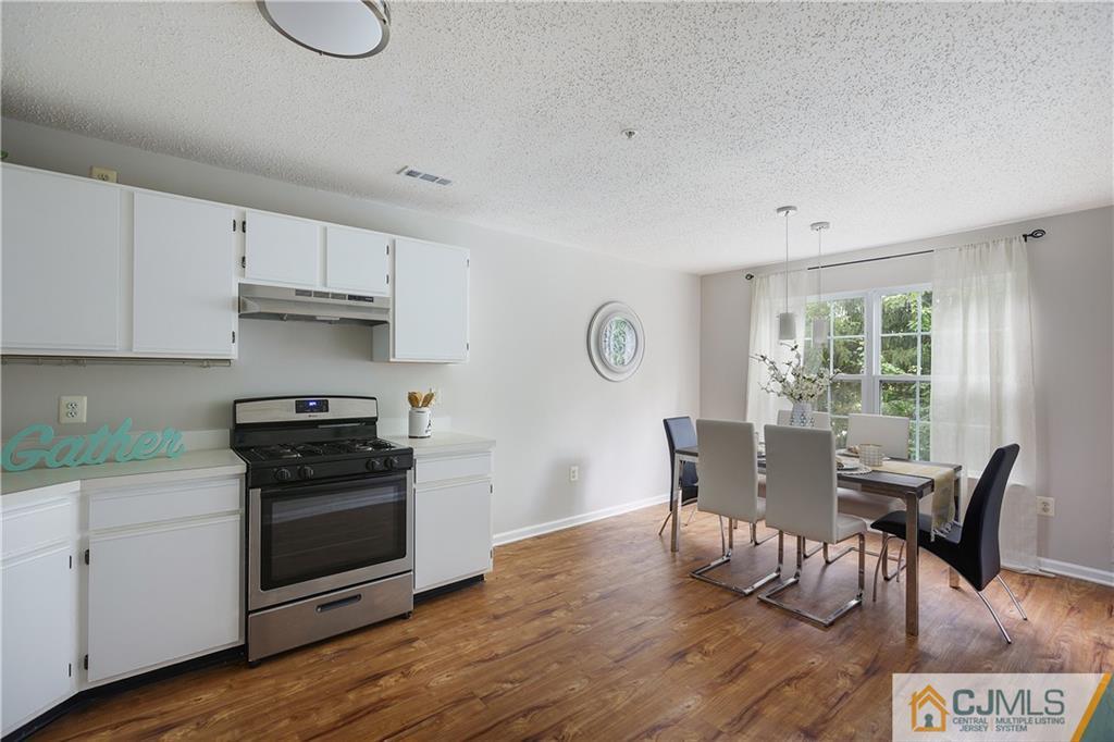 53 Prestwick Way Edison, NJ 08820 - Photo 9 of 28 a kitchen with stainless steel appliances granite countertop a stove a refrigerator a dining table and chairs with wooden floor