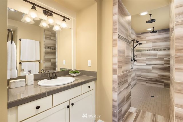 a bathroom with a granite countertop sink a mirror and shower