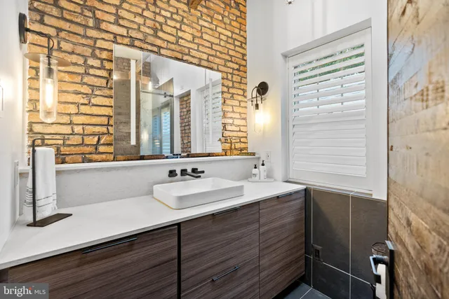 a bathroom with a sink a mirror and next to a window