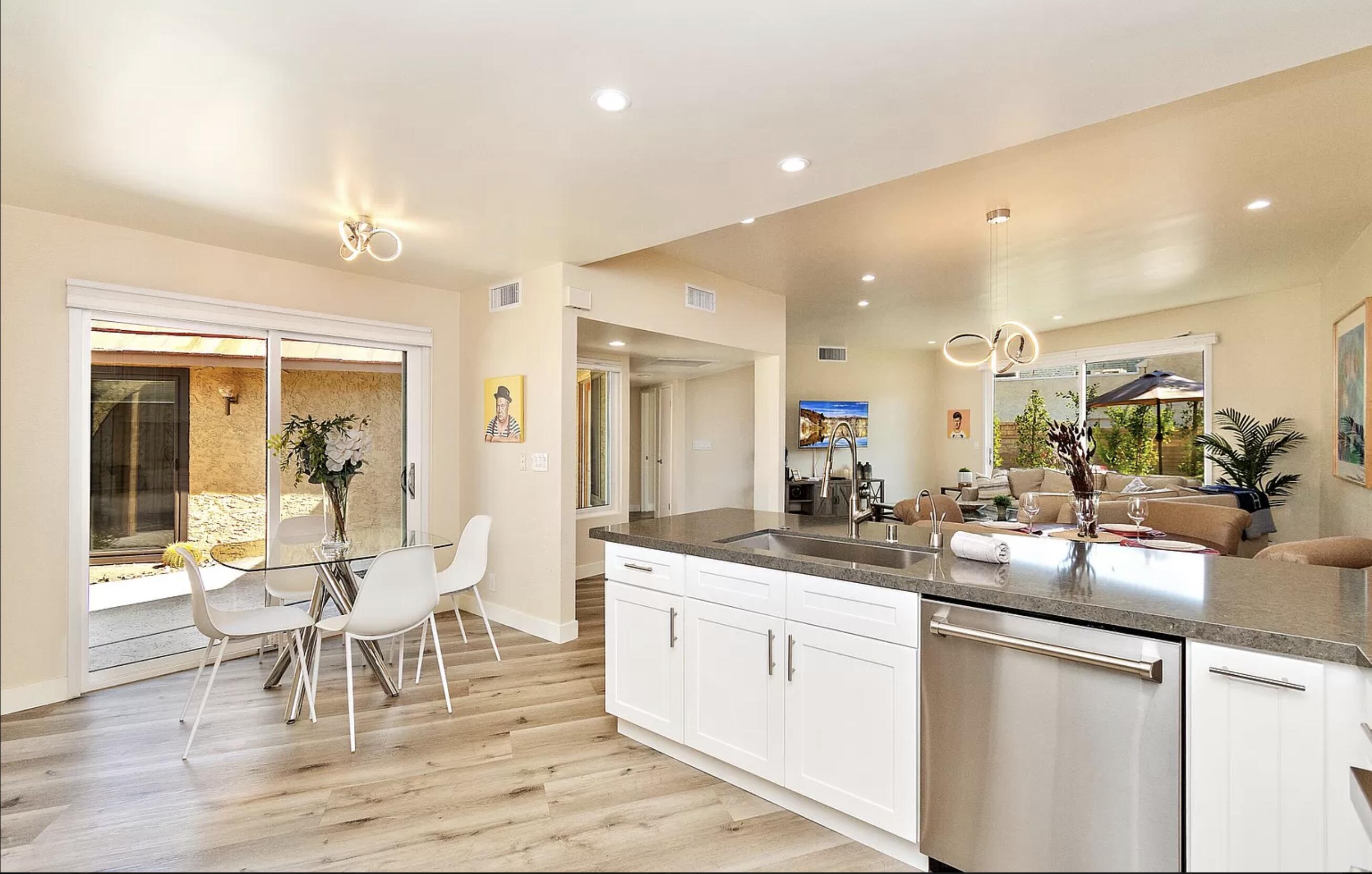 a dining hall with stainless steel appliances granite countertop a table and chairs in it