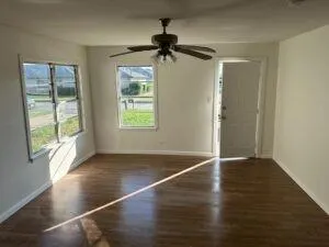 an empty room with wooden floor chandelier and windows