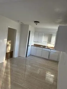 a view of an empty room with window and wooden floor