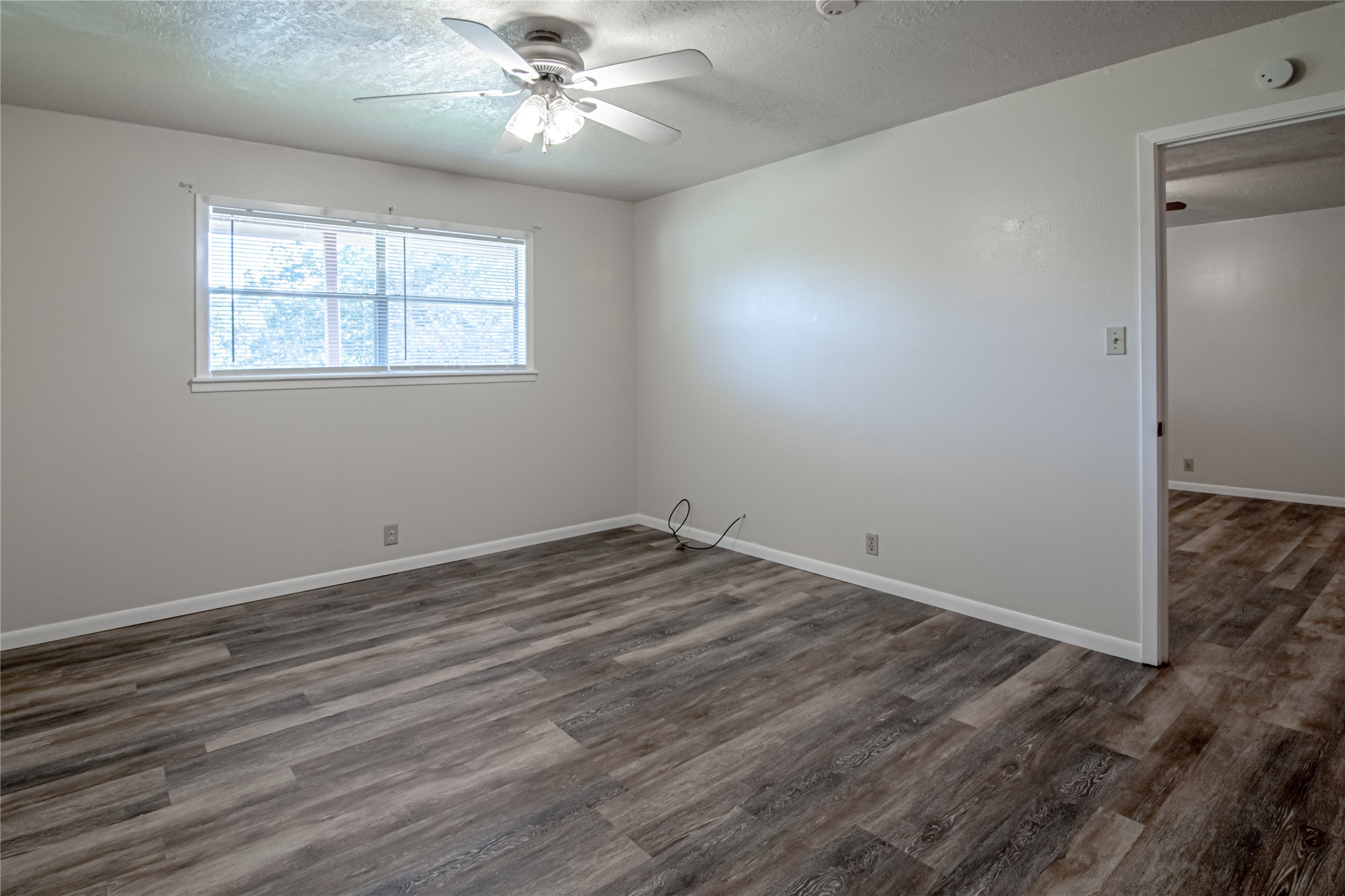 120 McAdams Lane, Unit F Huntsville, TX 77320 - Photo 14 of 21 an empty room with wooden floor chandelier fan and windows