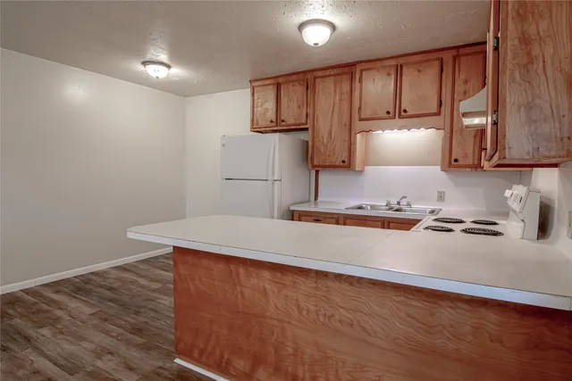 a kitchen with kitchen island a stove a sink and a refrigerator with wooden floor