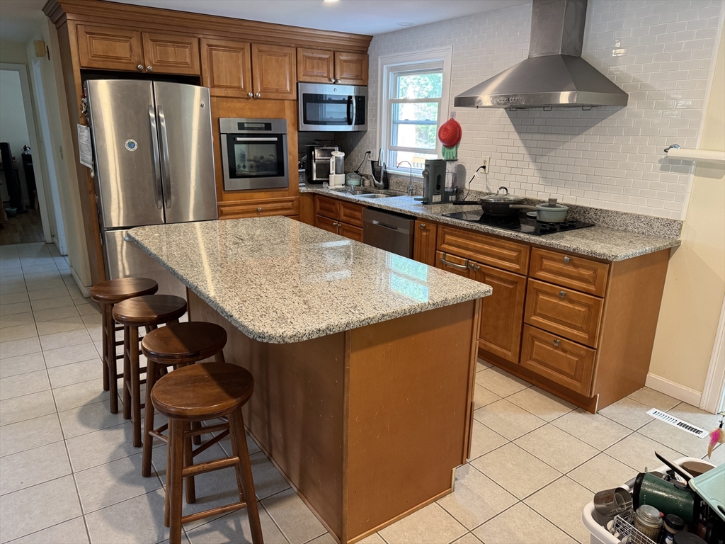 8 Heritage Road, Unit 1 Pelham, NH 03076 - Photo 3 of 13 a kitchen with stainless steel appliances granite countertop a sink a stove and a refrigerator