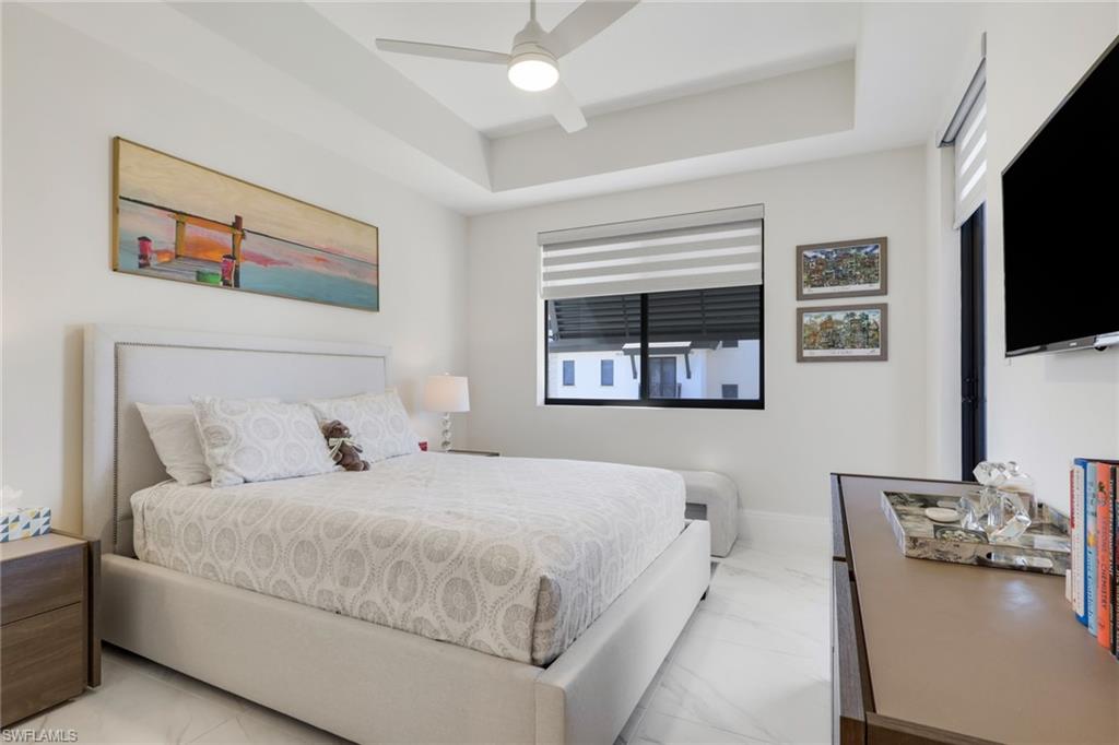 1135 3rd Avenue South, Unit 403 Naples, FL 34102 - Photo 16 of 34 Bedroom featuring a tray ceiling, ceiling fan, and marble look tiles