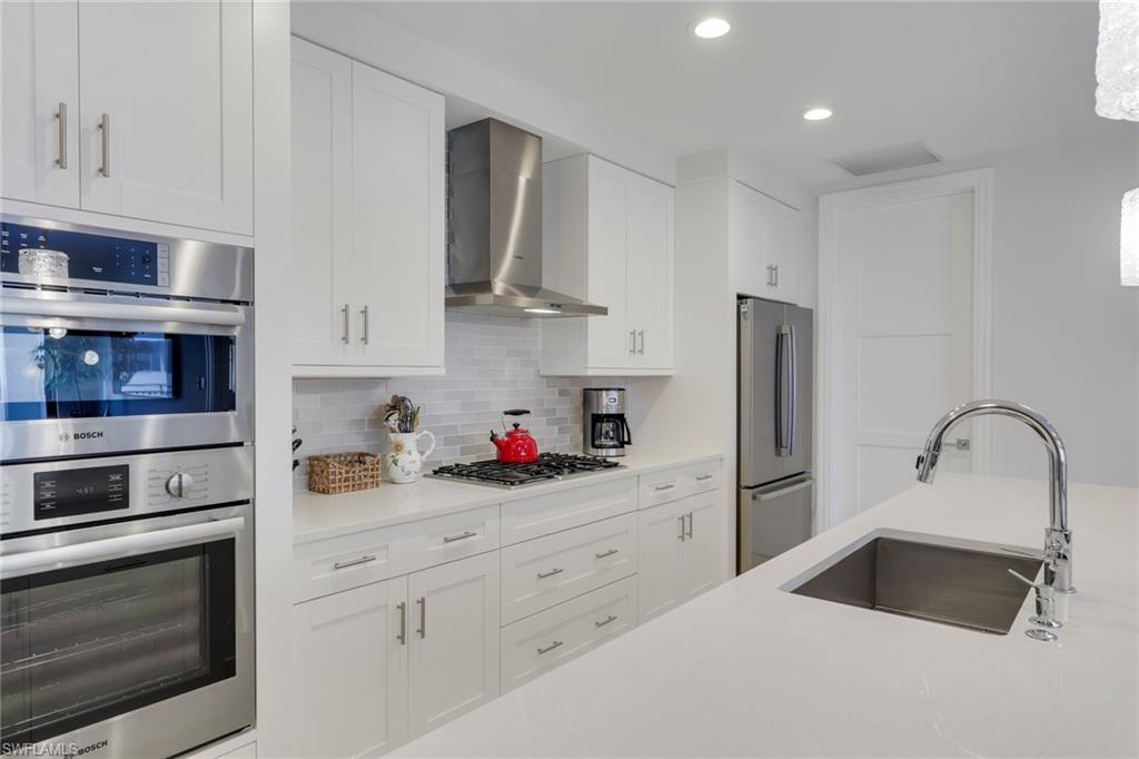 1135 3rd Avenue South, Unit 403 Naples, FL 34102 - Photo 4 of 34 Kitchen featuring stainless steel appliances, white cabinetry, backsplash, recessed lighting, and light stone counters