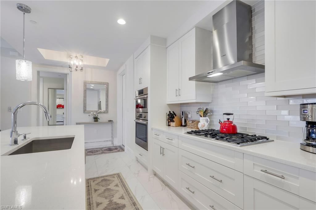 1135 3rd Avenue South, Unit 403 Naples, FL 34102 - Photo 6 of 34 Kitchen with white cabinetry, a skylight, light stone counters, and light marble finish flooring