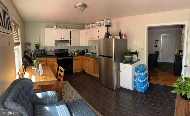 a kitchen with refrigerator and wooden floor