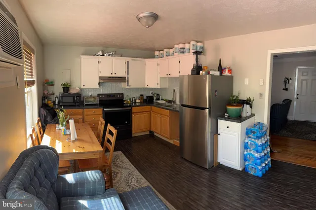 a kitchen with stainless steel appliances granite countertop a refrigerator a stove top oven a chimney and wooden floor