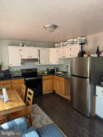a kitchen with granite countertop a refrigerator stove top oven and sink