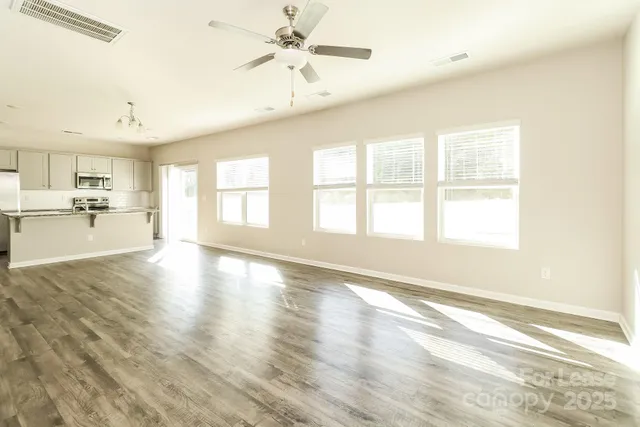 a view of an empty room with window and wooden floor