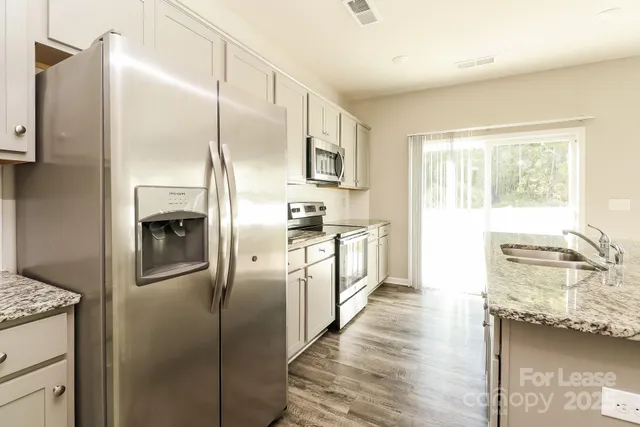a kitchen with stainless steel appliances granite countertop a refrigerator a stove and a sink with cabinets
