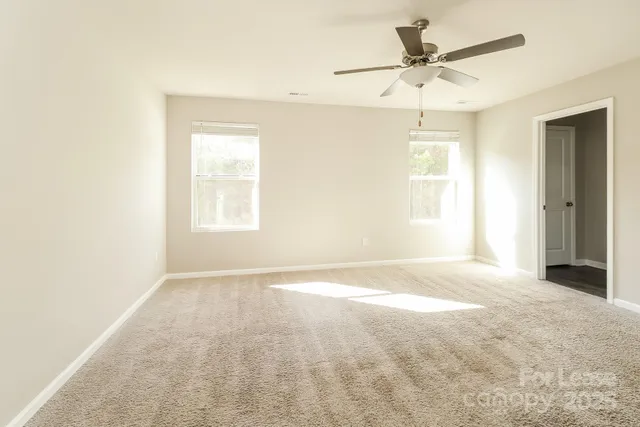 an empty room with a window and a fan