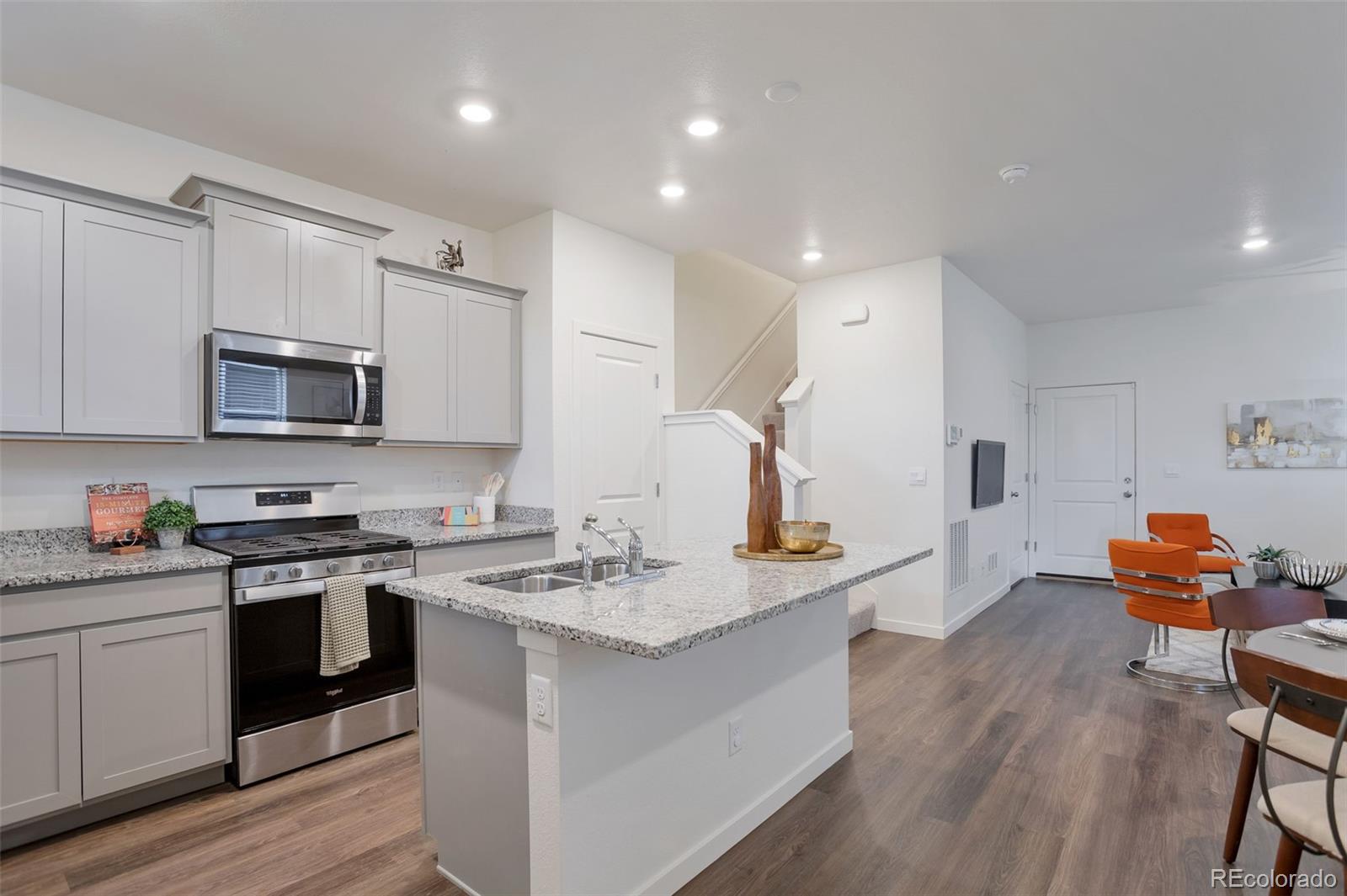 7017 Kali Court Frederick, CO 80530 - Photo 3 of 15 a kitchen with stainless steel appliances granite countertop a stove top oven a sink dishwasher and white cabinets with wooden floor