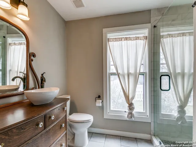 a bathroom with a granite countertop toilet sink and mirror