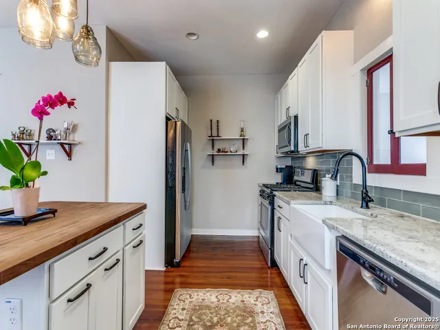 a kitchen view with stainless steel appliances kitchen island granite countertop a refrigerator and a stove top oven