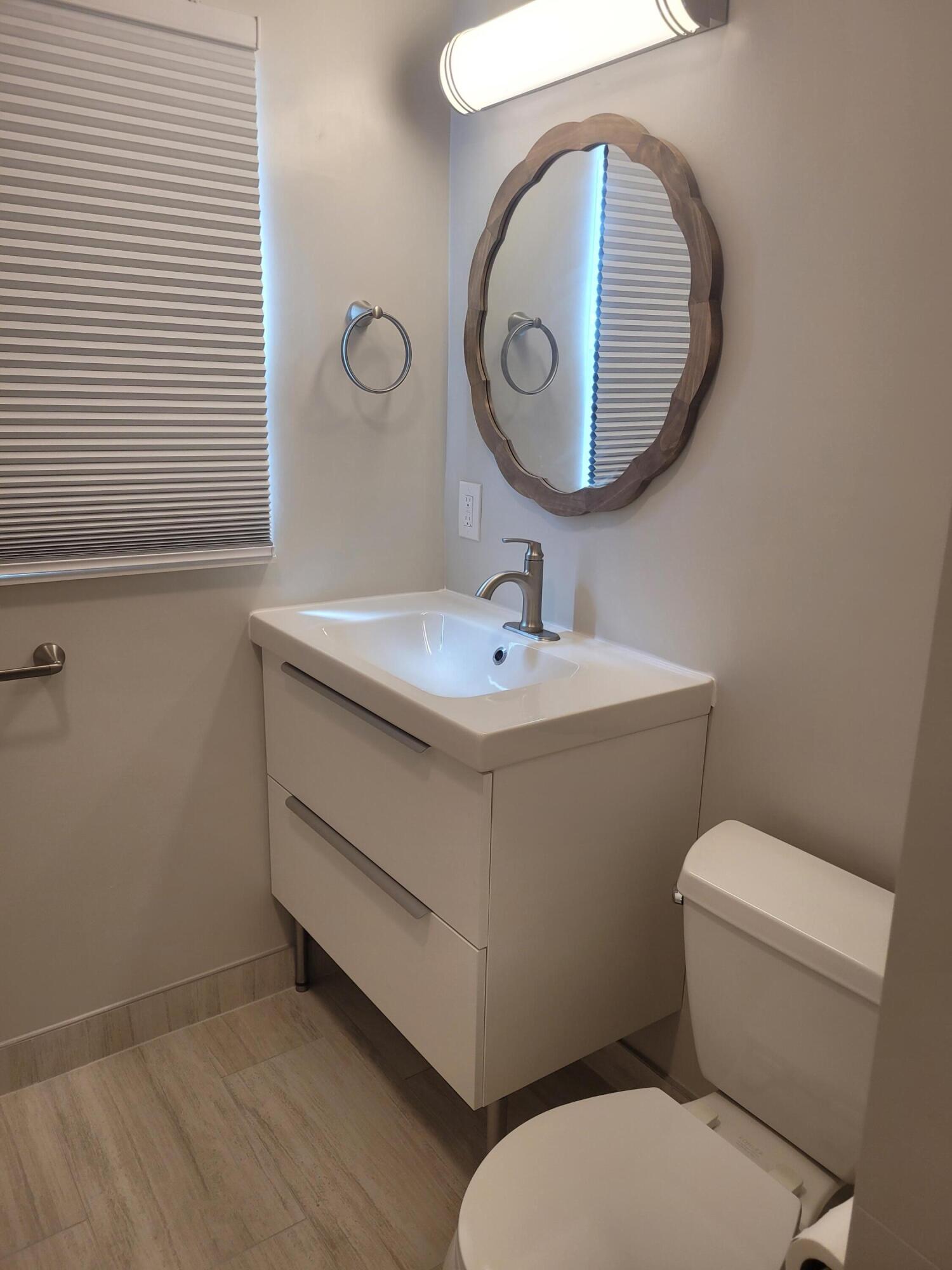 101 South Golfview Road, Unit 11 Lake Worth Beach, FL 33460 - Photo 6 of 28 a bathroom with a toilet sink and mirror
