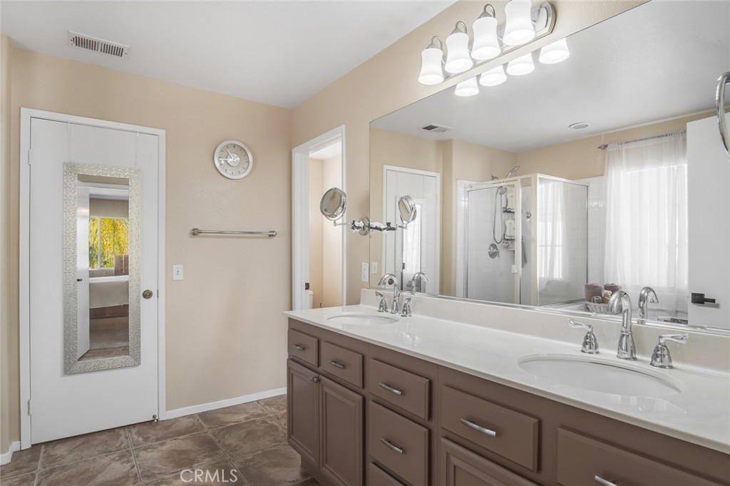 4330 Forest Ranch Way Oceanside, CA 92057 - Photo 24 of 51 The ensuite bath feels like a private spa, with dual sinks, ample drawers and cabinets, extra large mirror, upgraded tile flooring and elevated lighting. The walk-in closet is designed for comfort and function.
