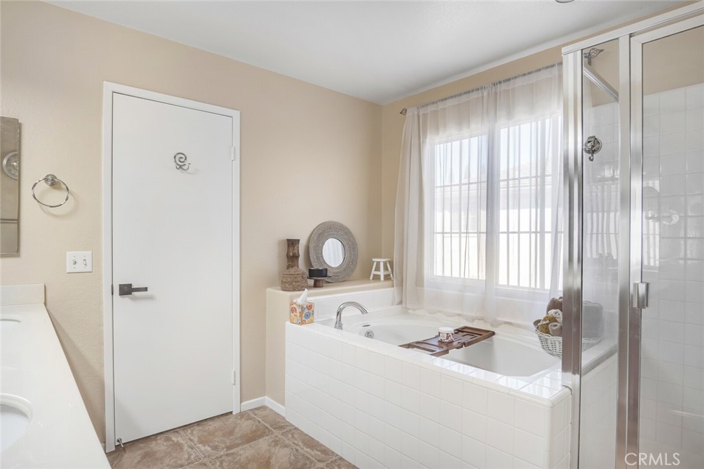 4330 Forest Ranch Way Oceanside, CA 92057 - Photo 25 of 51 A luxurious soaking tub sits beneath a large window, offering a peaceful view and natural light for morning routines. The glass-enclosed shower adds a sleek, modern touch, complemented by high-end finishes throughout.