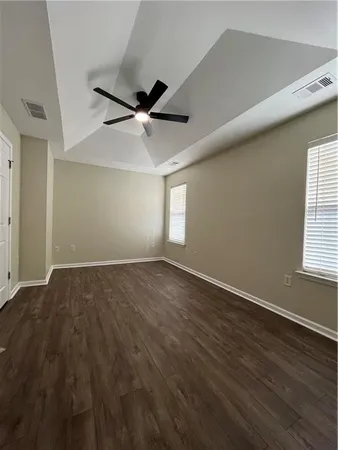 an empty room with wooden floor fan and windows