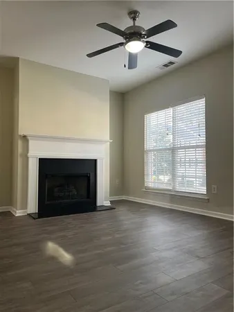 a view of an empty room with wooden floor fireplace and a window