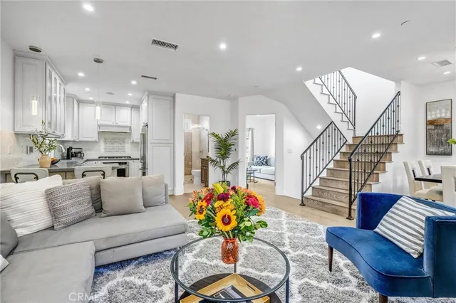 a living room with furniture kitchen view and a chandelier